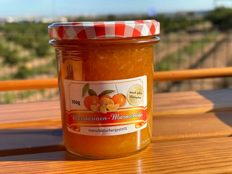 Glas Mandarinen-Marmelade auf einem Holztisch vor der Plantage